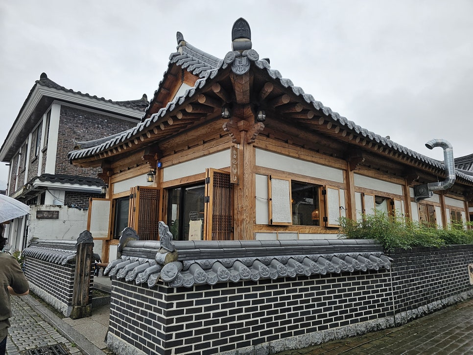 기와를 얹은 낮은 담장과 따뜻한 나무 질감이 어우러진 하와이안레시피 외관.